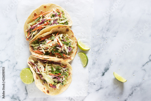 Tacos with guacamole and coleslaw served with lime slices on a light background. photo