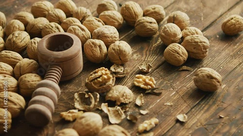 Closeup shot of fresh walnuts and wooden tool for cracking nuts lying on lumber tabletop