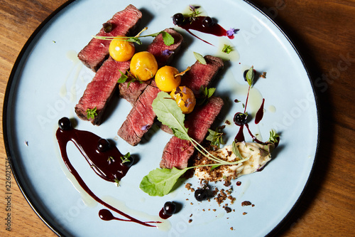 Close up of beef steak with cherry berries and salad served on plate
