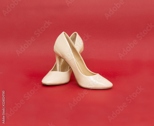 Beige high heel shoes on red