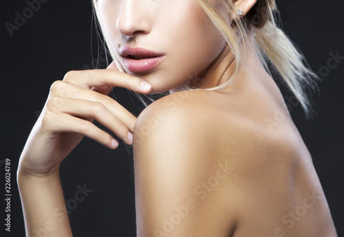 Attractive model girl beauty part of face with beauty spot, clean skin, natural nude makeup hold hand near chin, blond hair. Black background. Skincare health concept photo