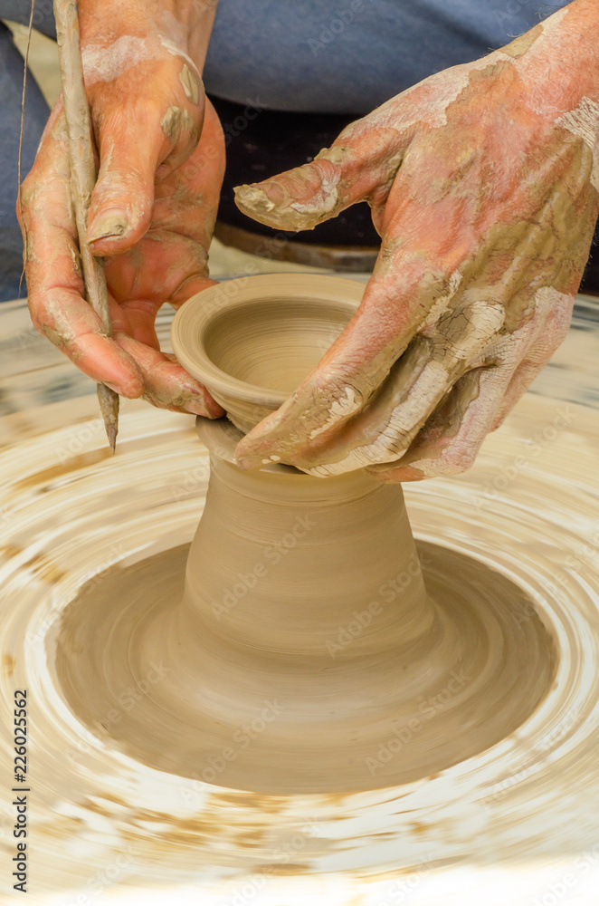 Closeup of the hands of the artist creating a clay pot, the traditional method of creating ceramic products
