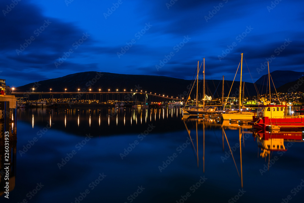 Night view of marina area in Tromso with Tromso Bridge in the distance - long exposure.