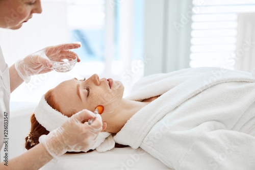 Doctor applies Hydro gel Mask on the woman. Before young woman receiving laser treatment. photo