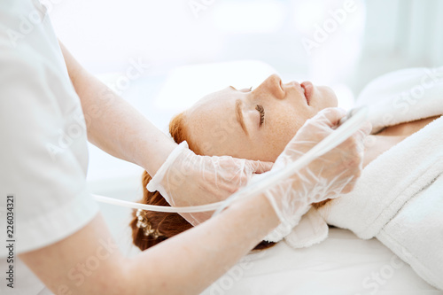 Face Beauty Treatment. Close up of female client getting facial gas-liquid oxygen water epidermal peeling using hardware apparatus photo