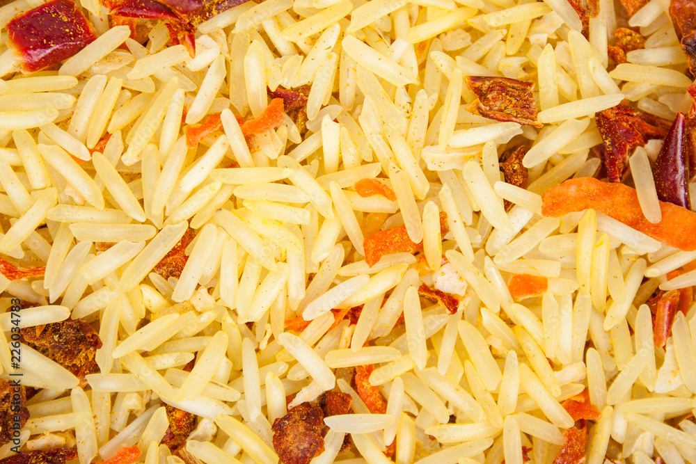 Background texture of basmati rice with dried carrots, onions, paprika, tomato, garlic and ground spices (turmeric, coriander and chili pepper). Top view. Close-up. Background texture of basmati rice with dried carrots, onions, paprika, tomato, garlic and ground spices (turmeric, coriander and chili pepper). Top view. Close-up.