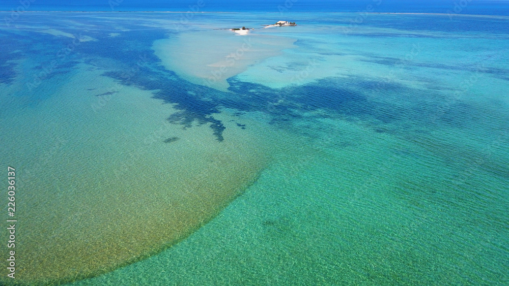 Aerial drone bird's eye view photo of tropical and exotic coral reef forming an atoll archipelago with beautiful sapphire and turquoise open ocean