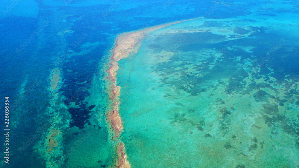 Aerial drone bird's eye view photo of tropical and exotic coral reef forming an atoll archipelago with beautiful sapphire and turquoise open ocean