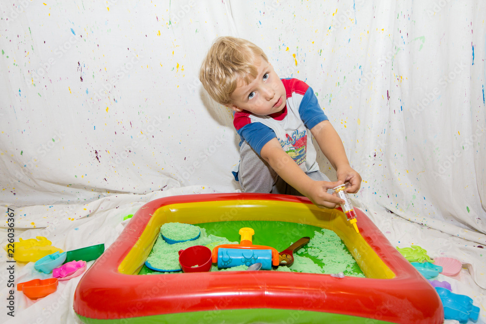 Fototapeta premium children play in an inflatable pool with kinetic sand