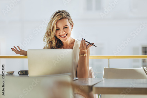Businesswoman looking at laptop and smiling at cafe