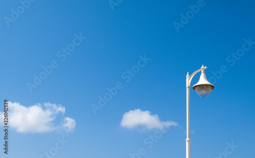 historic white street lamp with text space in the blue sky background with white clouds