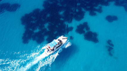 Aerial bird's eye view photo taken by drone of boat cruising in caribbean tropical beach with turquoise - sapphire waters