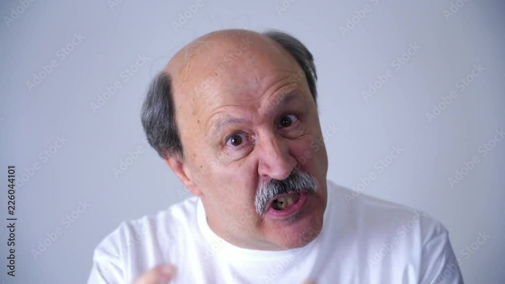 Disappointed and angry man point his finger in facial emotion expression of senior 60s 70s year old man in studio on grey background in face expression concept. Disappointed and angry man point his finger in facial emotion expression of senior 60s 70s year old man in studio on grey background in face expression concept.