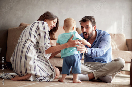 Young family is having fun playing with a baby at home.