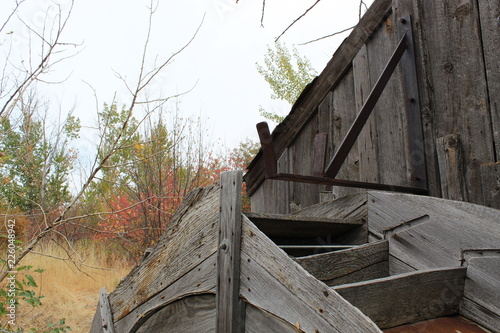 old wooden water wheel in the woods, sun faded wood aged and non operable , wood is grey in color from weather and sun. photo