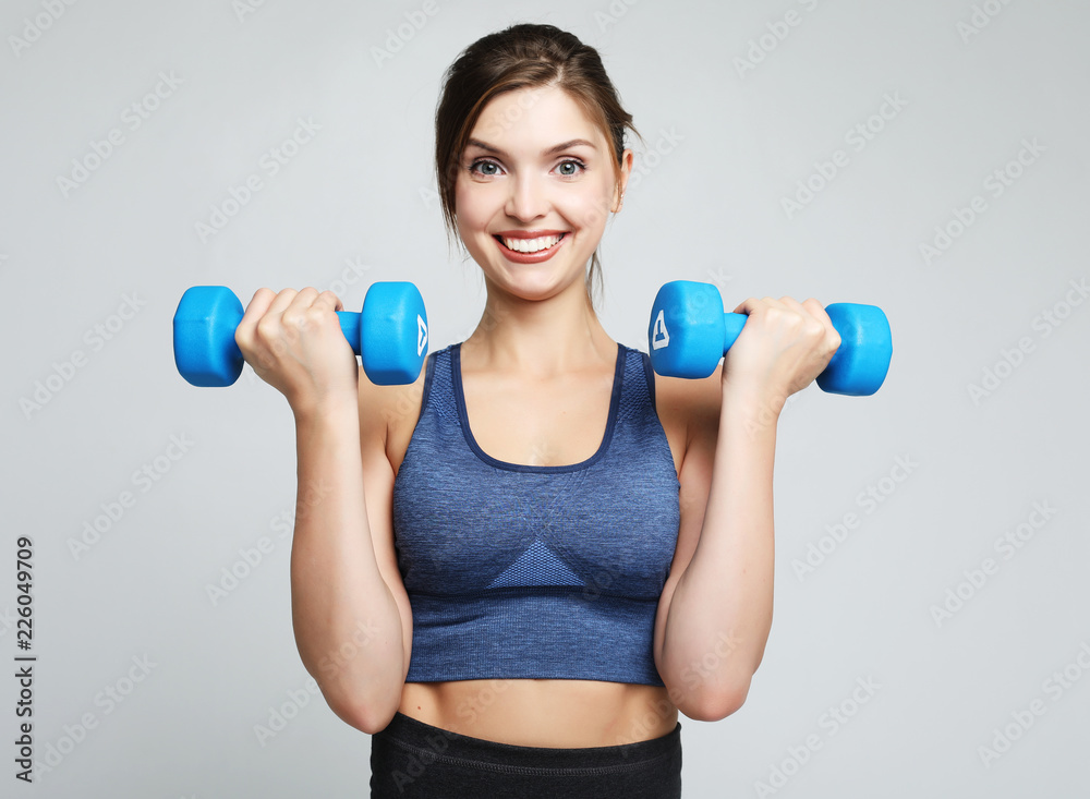 Picture of fit and healthy young woman smiling and holding dumbbelsl to shoulder. Sport and people concept. Picture of fit and healthy young woman smiling and holding dumbbelsl to shoulder. Sport and people concept.