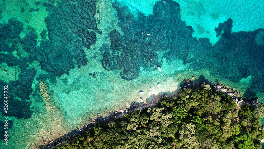 Aerial photo of iconic white cliff tropical bay forming a blue lagoon with deep turquoise clear ocean and docked small boats enjoying this unique paradise