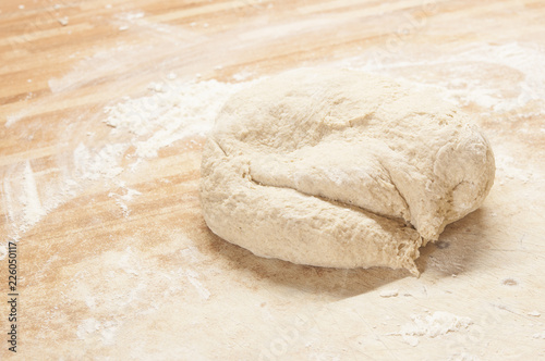 Whole wheat pizza dough shaped into ball on floured wooden background