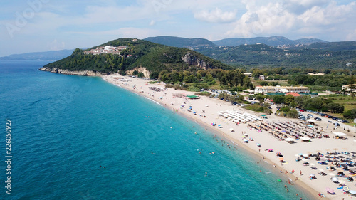 Aerial drone bird's eye view of popular beach of Karavostasi with beautiful clouds and turquoise sandy beach full of sunbeds at summertime, Epirus, Ionian, Greece