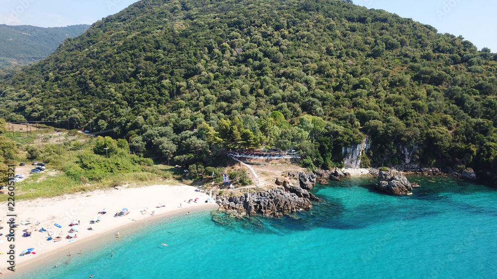 Obraz premium Aerial drone bird's eye view of popular beach of Karavostasi with beautiful clouds and turquoise sandy beach full of sunbeds at summertime, Epirus, Ionian, Greece