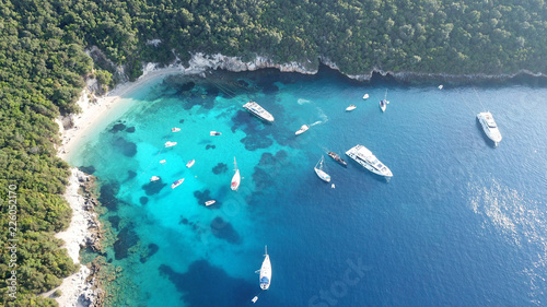 Aerial photo of tropical exotic paradise vegetated island with blue lagoon, white sandy beaches and turquoise sea with sail boats and yachts docked