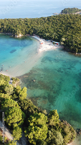 Aerial drone bird's eye view photo of popular and iconic turquoise beach of Bella Vraka in island of Mourtemeno with sunbeds and canoes forming a blue lagoon, Sivota bay, Epirus, Greece