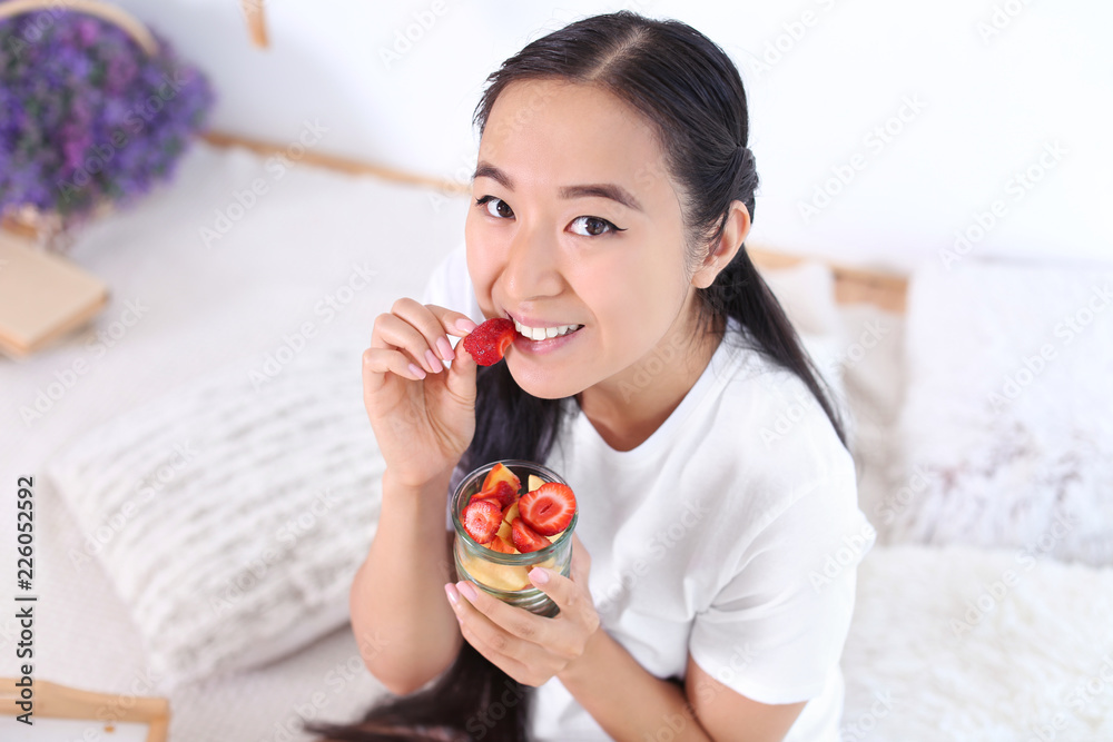 Asian woman eating healthy fruit salad at home Asian woman eating healthy fruit salad at home