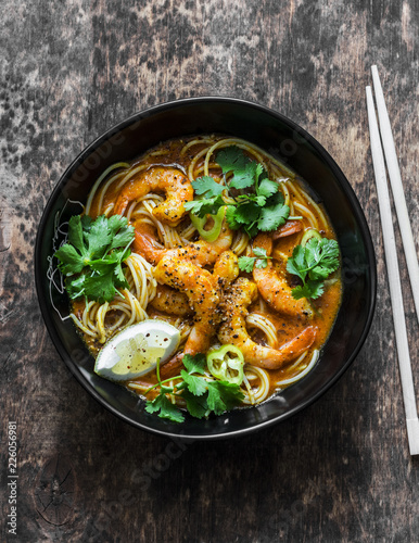 Shrimp laksa soup on a dark wooden background, top view. Copy space. Asian style food