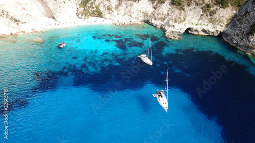 Aerial drone bird's eye view photo of sail boats docked in tropical caribbean paradise bay with white rock caves and turquoise clear sea
