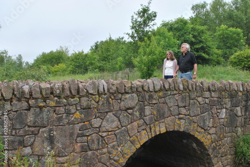 man and woman walking over stone bridge