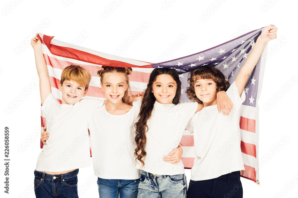 Obraz premium smiling adorable children standing under american flag and looking at camera isolated on white