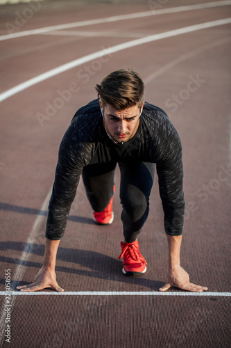 Male athlete on starting position at running track. Runner practicing run in stadium racetrack