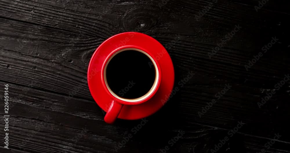 From above view of red cup of coffee with saucer on wooden background 