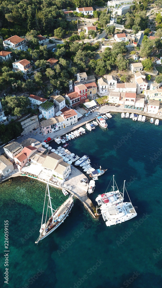 Aerial drone bird's eye view photo of iconic small port and fishing village of Logos with traditional Ionian architecture and sail boats docked, Paxos island, Ionian, Greece