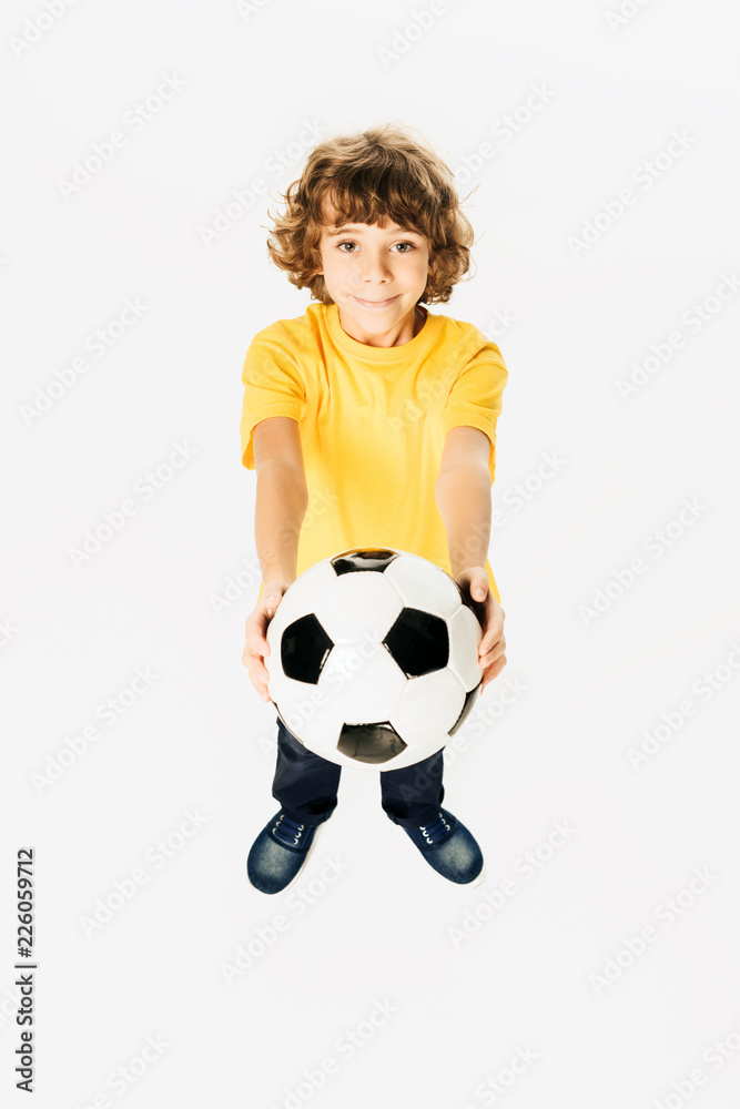 high angle view of adorable boy holding soccer ball and smiling at camera isolated on white
