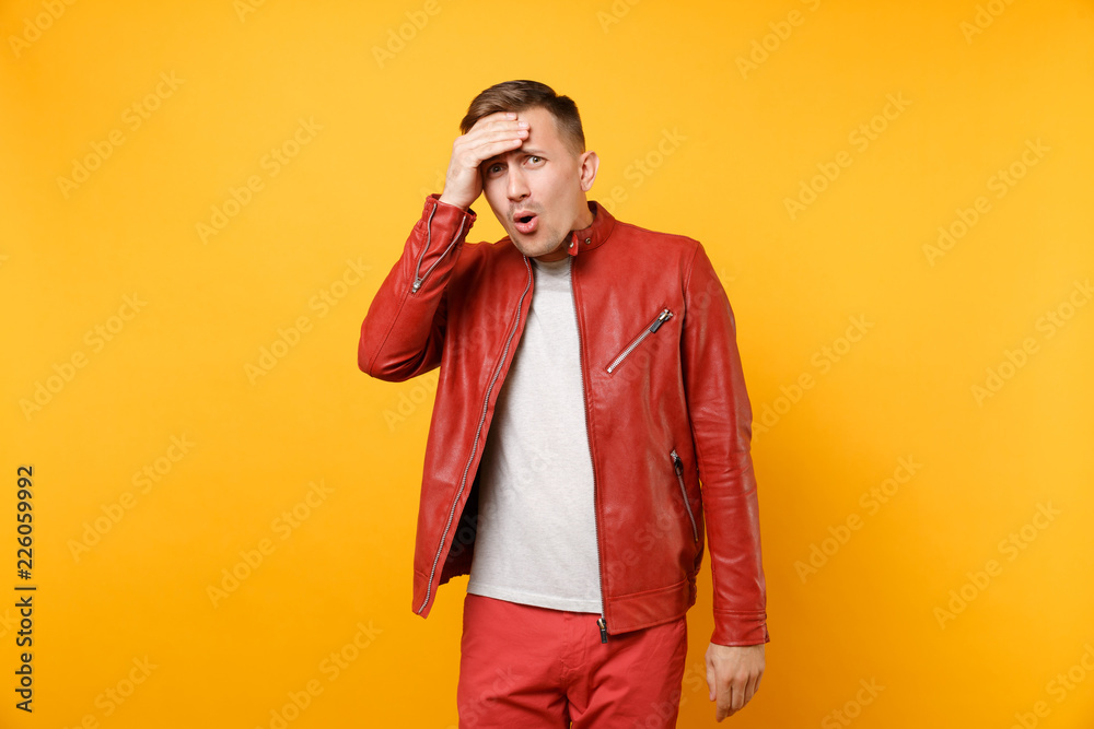 Portrait vogue shocked handsome young man 25-30 years in red leather jacket, t-shirt standing isolated on bright trending yellow background. People sincere emotions lifestyle concept. Advertising area Portrait vogue shocked handsome young man 25-30 years in red leather jacket, t-shirt standing isolated on bright trending yellow background. People sincere emotions lifestyle concept. Advertising area