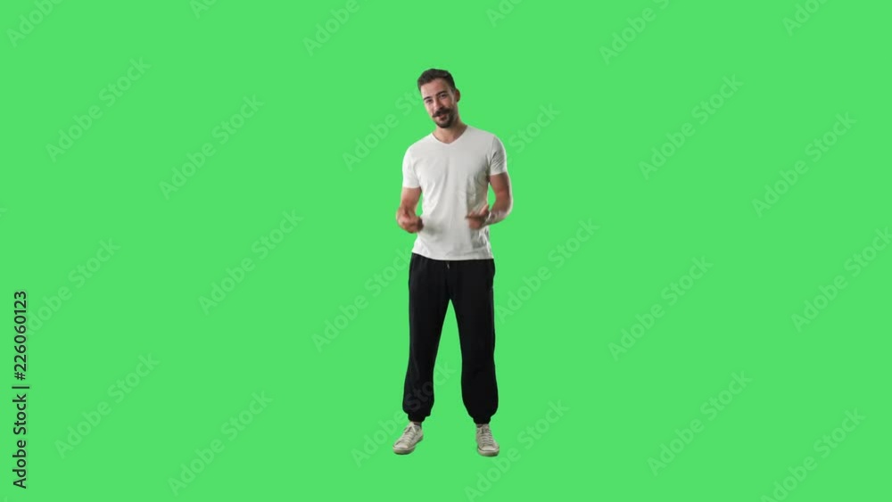 Happy young relaxed casual man talking and explaining while gesticulating hands looking at camera. Full body isolated on green screen background. 