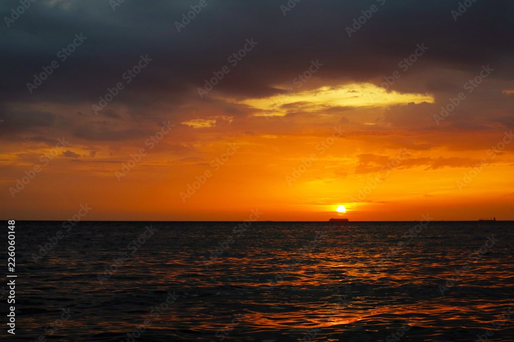 sunset and ship on horizontal ocean water surface colorful cloud sky