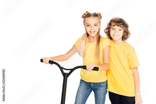 cute happy kids standing with scooter and smiling at camera isolated on white