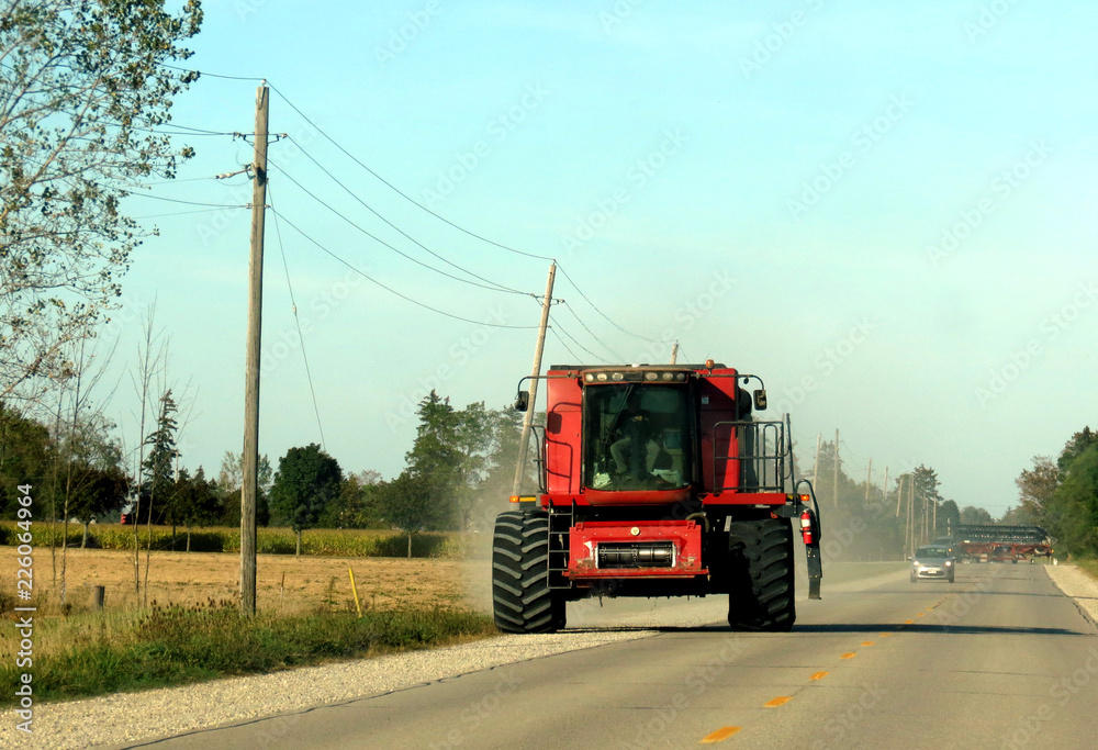 Naklejka premium A farmer driving a giant tractor along the highway.