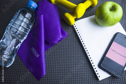 Time for diet slimming weight loss concept. Sport fitness, apple, sneakers, bottle of water and yellow weights on grey rubber background. Vintage retro instagram filter