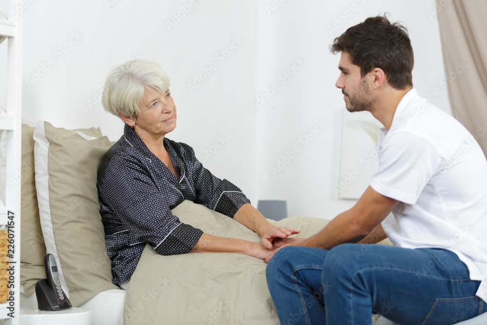 senior lady and her young male carer holding hands senior lady and her young male carer holding hands
