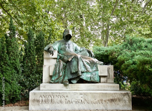 Statue of Anonymous in Budapest, Hungary surrounded by green trees.
