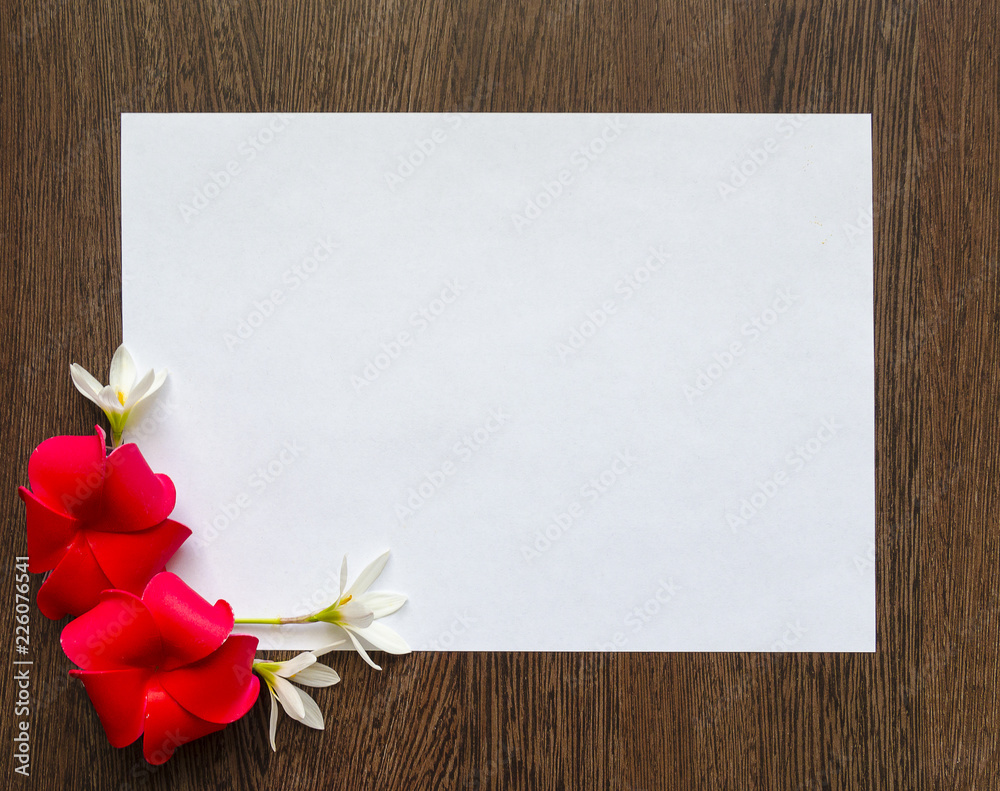 Empty white sheet of paper for text on a dark wood background. Background with flowers frame. Mockup