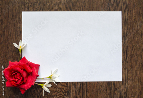 Empty white sheet of paper for text on a dark wood background. Background with flowers frame