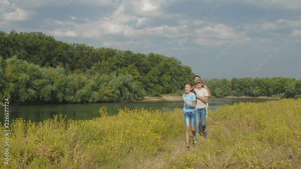 Sports family involved in sports in nature. A child runs with parents along the river. Sports family involved in sports in nature. A child runs with parents along the river.