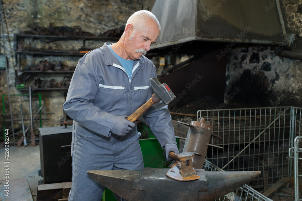 Metalworker at anvil, holding hammer Metalworker at anvil, holding hammer