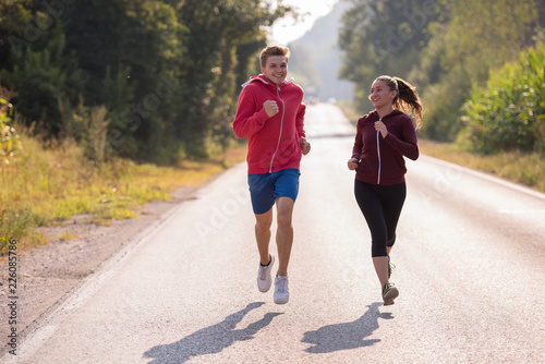 young couple jogging along a country road