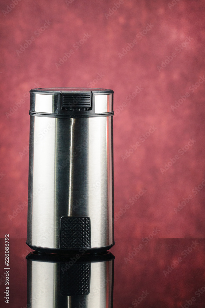 Coffee grinder on the red mirror background Coffee grinder on the red mirror background