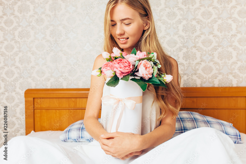 beautiful girl with peony flowers sitting on the bed. She just woke up and got a bouquet of flowers beautiful girl with peony flowers sitting on the bed. She just woke up and got a bouquet of flowers